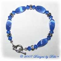 Designs by Debi Handmade Jewelry Blue Cat's Eye Twist Beads, Swarovski Crystal Sapphire Bicones and Silver Floral Rondelles Bracelet with a Silver Round Toggle Clasp