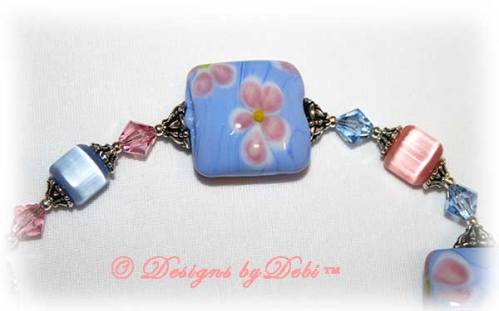 Designs by Debi Handmade Jewelry Sweet Angels one of a kind ooak handmade light pink and light blue lampwork and crystal bracelet made in honor of national pregnancy and infant loss awareness month to raise money for Missing GRACE Foundation. It was made with pink flowers on blue handmade square lampwork beads, pink and blue cat's eye beads, pink and blue crystals and sterling silver with a flower toggle clasp.