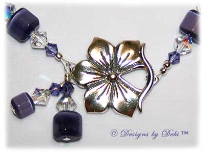 Designs by Debi Handmade Jewelry Purple Pansies one of a kind ooak handmade tanzanite purple lampwork and crystal bracelet made in honor of national alzheimer's disease awareness month to raise money for the Alzheimer's Association. It was made with purple flowers on pale lavender handmade square lampwork beads with amethyst scrolls, purple cat's eye beads, crystal ab and tanzanite crystals and sterling silver with a pansy flower toggle clasp.